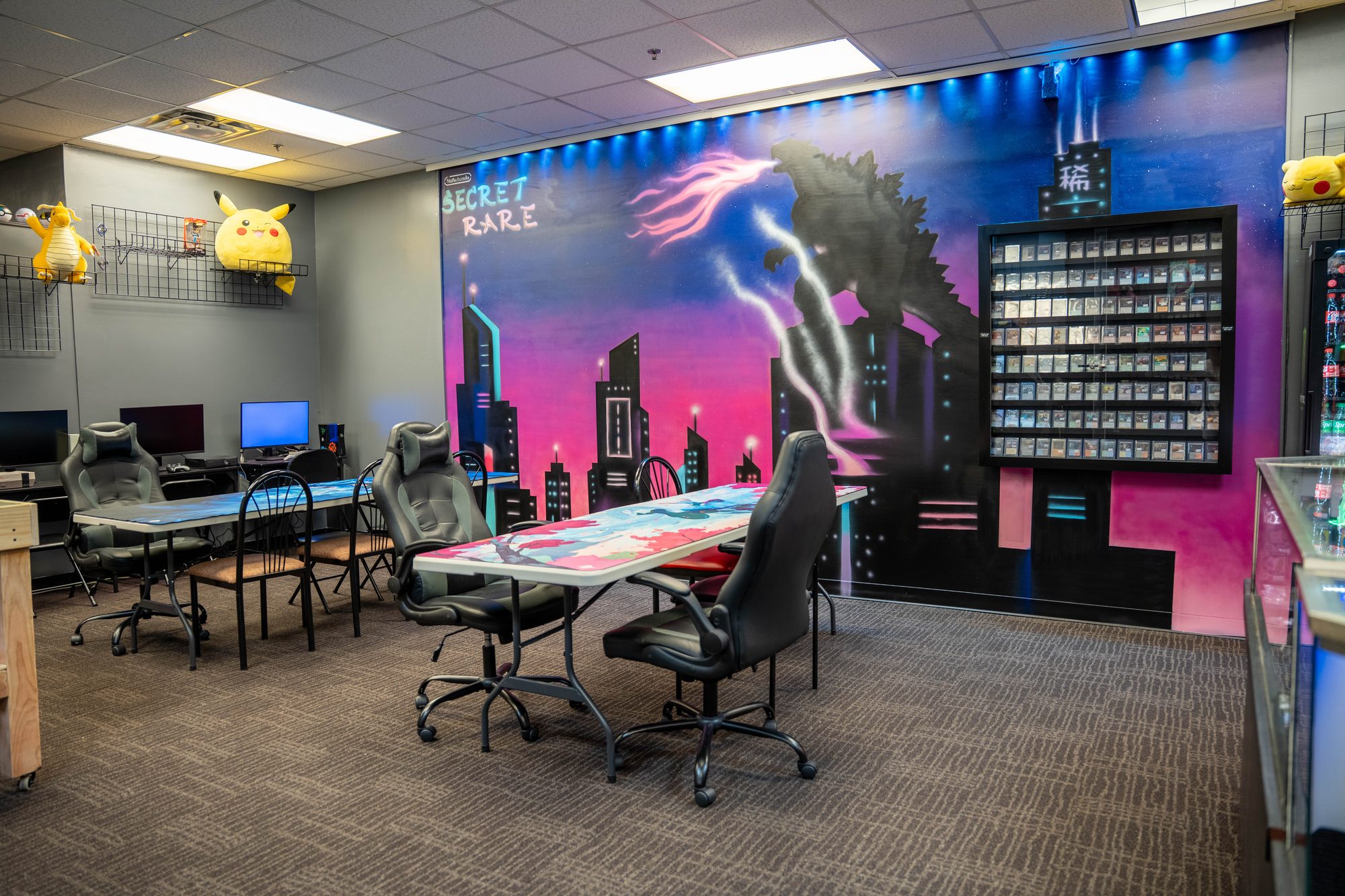 The Secret Rare Gaming play space with neon synthwave city mural and gaming tables