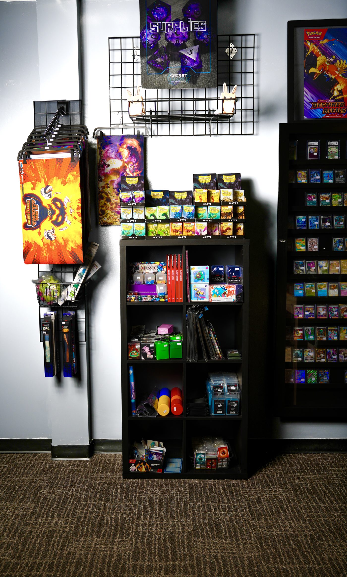 Wall of playmats, Dragon Shield sleeves, dice and card supplies